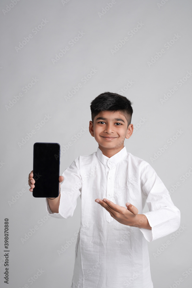 Cute indian little boy showing smart phone screen with copy space over white background Cute indian little boy showing smart phone screen with copy space over white background