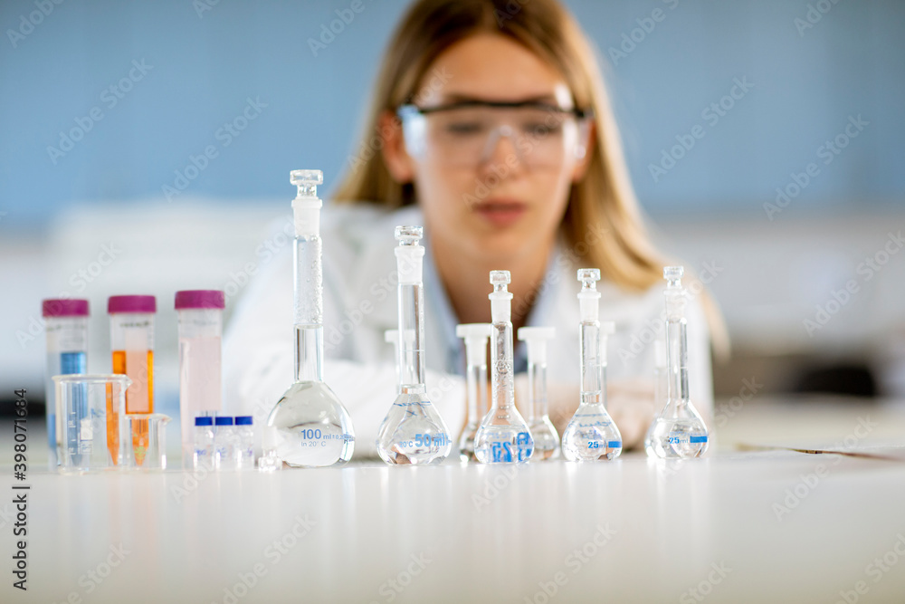 Fototapeta premium Female medical or scientific researcher looking at a flasks with solutions in a laboratory