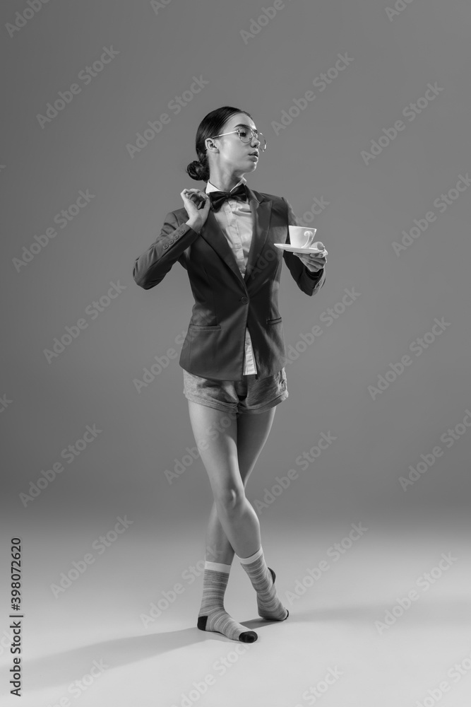 Coffee time. Young fashionable, stylish woman wearing jacket and socks working from home. Fashion during insulation 'cause of coronavirus pandemic. Half business and half home style. Black and white. Coffee time. Young fashionable, stylish woman wearing jacket and socks working from home. Fashion during insulation 'cause of coronavirus pandemic. Half business and half home style. Black and white.