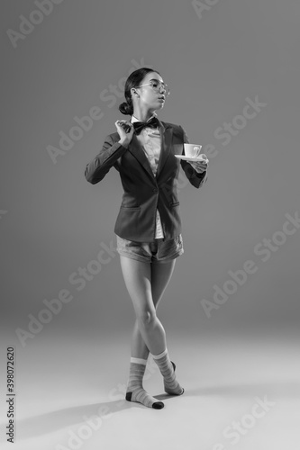 Coffee time. Young fashionable, stylish woman wearing jacket and socks working from home. Fashion during insulation 'cause of coronavirus pandemic. Half business and half home style. Black and white.