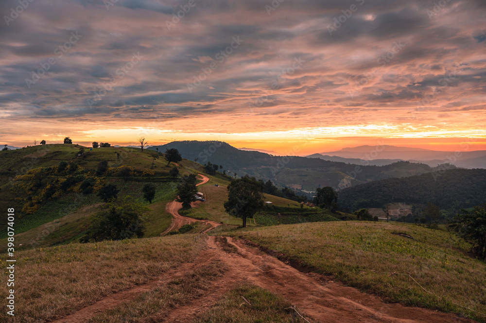Obraz premium Sunrise on farmland hill with colorful sky and tourists camping on vacation in national park
