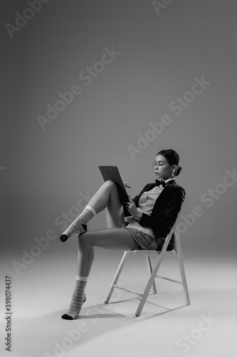 Offer. Young fashionable, stylish woman wearing jacket and socks working from home. Fashion during insulation 'cause of coronavirus pandemic. Half business and half home style. Black and white.