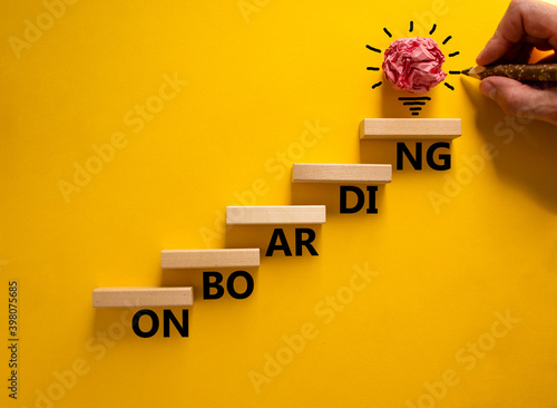 Success onboarding process symbol. Wood blocks stacking as step stair on yellow background, copy space. Businessman hand and light bulb. Word 'onboarding'. Business and onboarding concept. photo