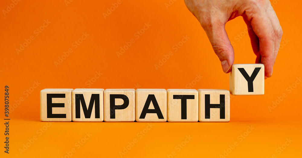 Empathy symbol. Concept word 'empathy' on wooden cubes on a beautiful orange background. Male hand. Psychological and empathy concept, copy space. - obrazy, fototapety, plakaty 