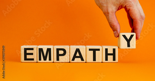 Empathy symbol. Concept word 'empathy' on wooden cubes on a beautiful orange background. Male hand. Psychological and empathy concept, copy space.