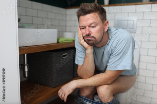 Man sit on toilet with constipation and wait for laxative to take effect. Digestive system disease and treatment. photo