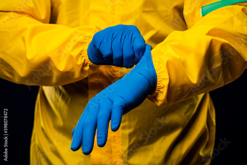 The scientist wears a yellow decontamination suit and wears blue rubber gloves to protect his skin. photo