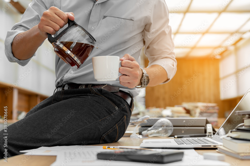 Businessman pouring coffee into a cup in office