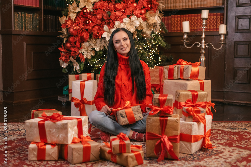woman in a knitted hat with New Year's gifts on a red background