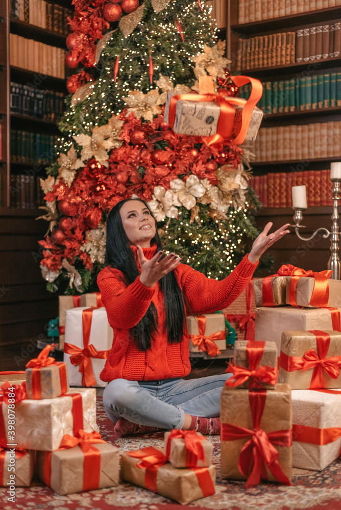 girl in a red sweater catches gifts in the air on a red background