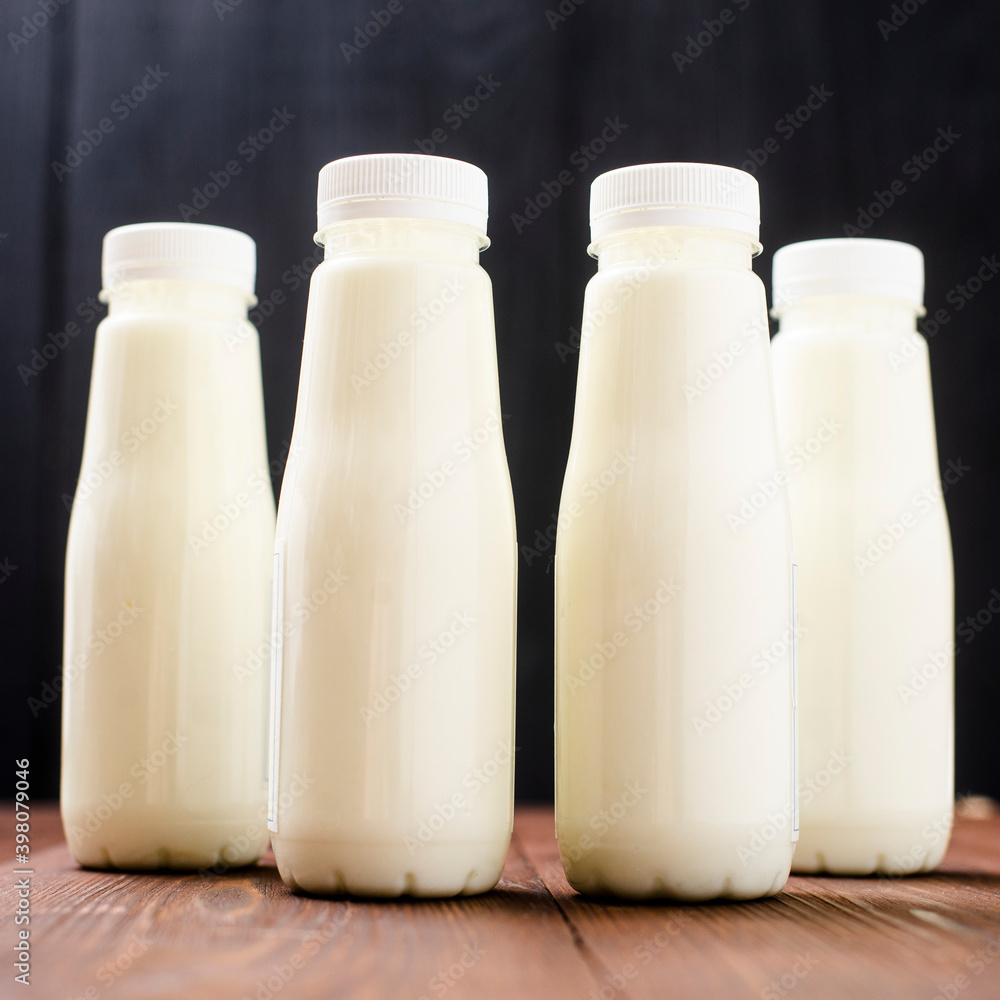 Bottles with milk, yogurt on a wooden background. Natural dairy products. Bottles with milk, yogurt on a wooden background. Natural dairy products.