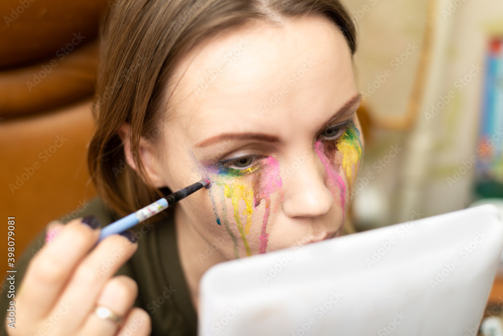 Bad makeup concept. Woman with multi-colored tears from paints. Bad makeup concept. Woman with multi-colored tears from paints.