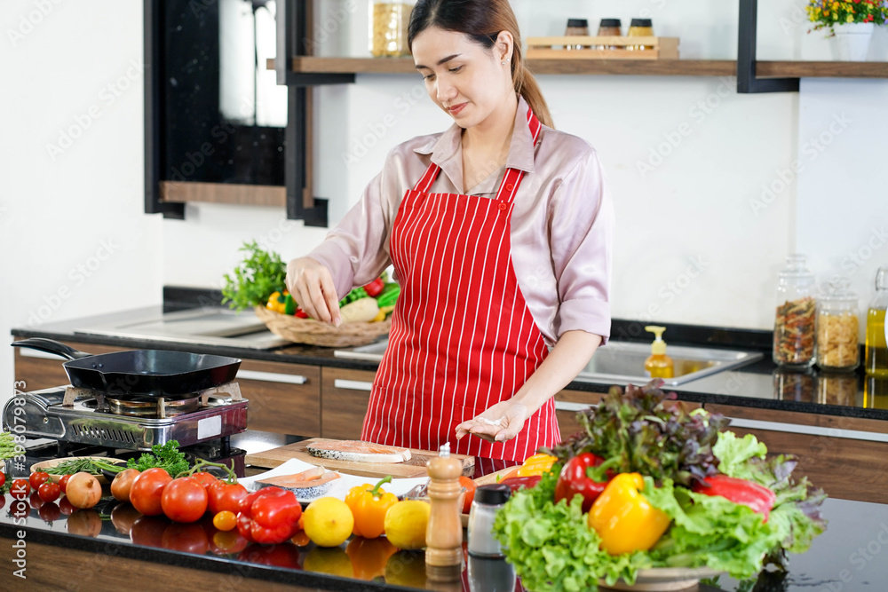 Asian beautiful woman cooking organic meal fish in kitchen Asian beautiful woman cooking organic meal fish in kitchen