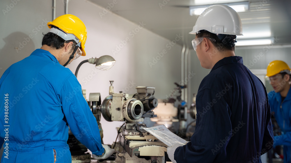 Leader inspect mechanic operating lathe grinding machine at factory. Leader inspect mechanic operating lathe grinding machine at factory.