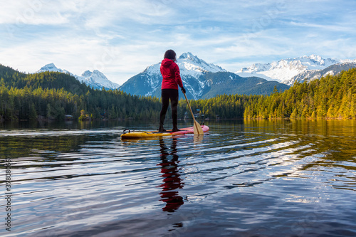 Adventurous Girl Paddle Boarding on Levette Lake with famous Tantalus Mountain Range in the background. Taken in Squamish  North of Vancouver  British Columbia  Canada.