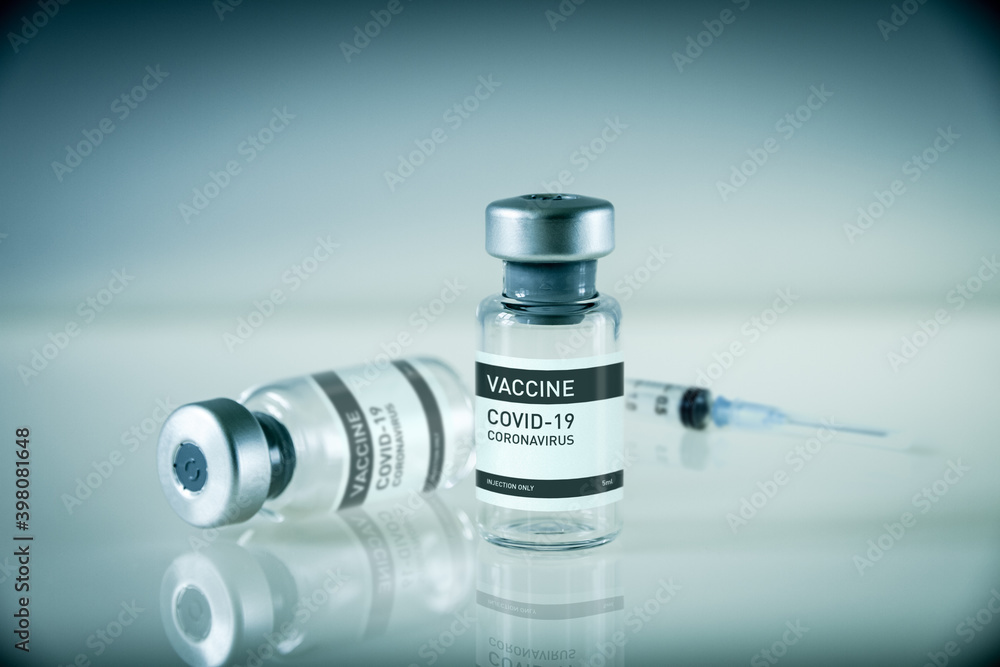 Covid-19 vaccine bottle and syringe on a blue background Covid-19 vaccine bottle and syringe on a blue background