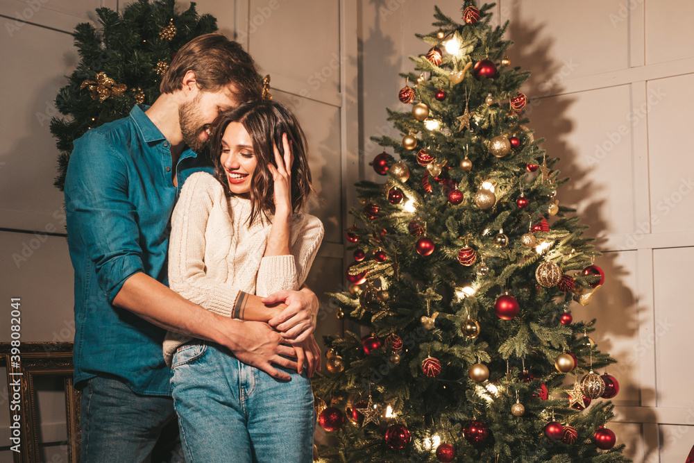 Smiling beautiful woman and her handsome boyfriend. Happy cheerful family posing in the interior near Christmas tree. Models hugging. Love, x-mas concept