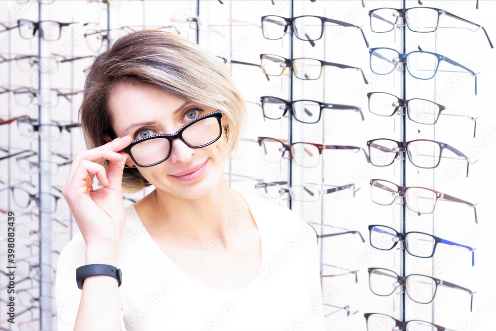 young woman in optic store choosing new glasses with optician. glasses in the store of optics. A woman chooses glasses. Emotions. Ophthalmology. young woman in optic store choosing new glasses with optician. glasses in the store of optics. A woman chooses glasses. Emotions. Ophthalmology.