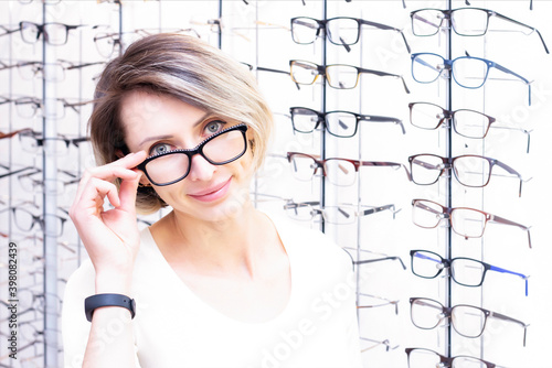 young woman in optic store choosing new glasses with optician. glasses in the store of optics. A woman chooses glasses. Emotions. Ophthalmology.