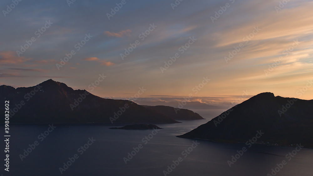 Stunning panoramic view of islands Kvaløya and Sessøya in the Norwegian Sea with colorful sky at sunset and rugged mountains viewed from Rekvik, Norway.