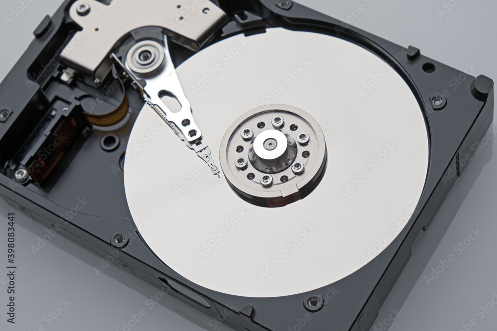 Disassembled HDD macro shot. Clean mirror surface with with magnetic needle on center. Broken hard drive storage and computer equipment on grey background. Disassembled HDD macro shot. Clean mirror surface with with magnetic needle on center. Broken hard drive storage and computer equipment on grey background.