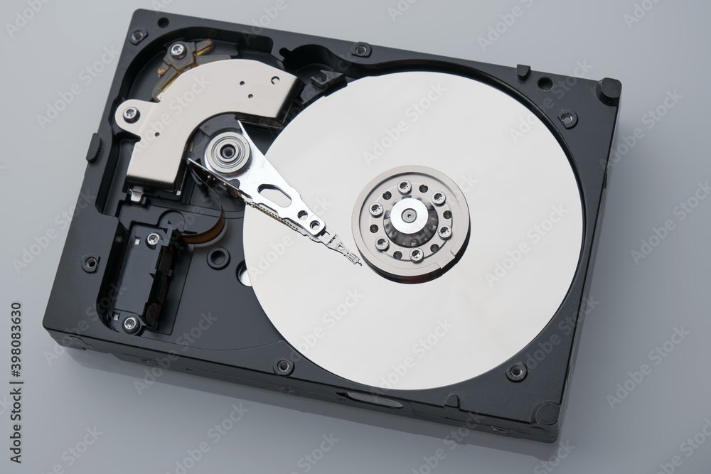 Disassembled HDD macro shot. Clean mirror surface with with magnetic needle on center. Broken hard drive storage and computer equipment on grey background. Disassembled HDD macro shot. Clean mirror surface with with magnetic needle on center. Broken hard drive storage and computer equipment on grey background.