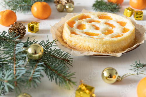 amerikanischer Cheesecake oder Käsekuchen mit orangen Mandarinen zur Weihnachtszeit im Winter auf einem Tisch aus Holz