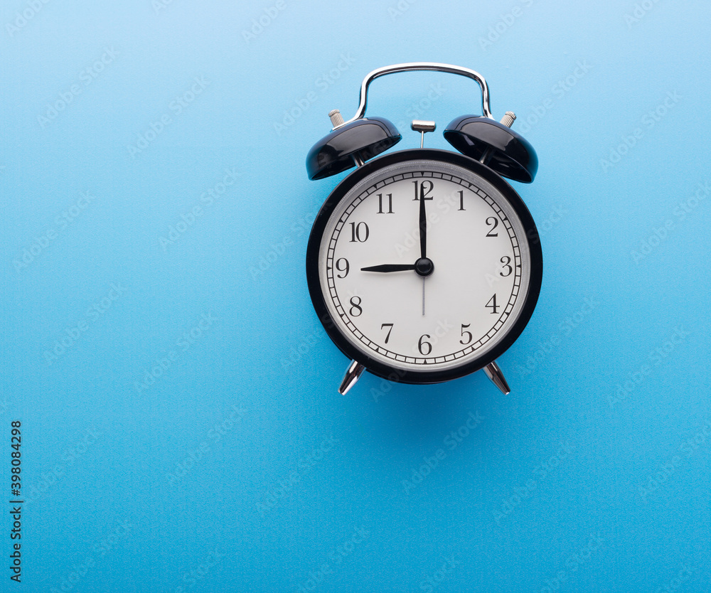 Black retro alarm clock showing nine o'clock, closeup top view clipping