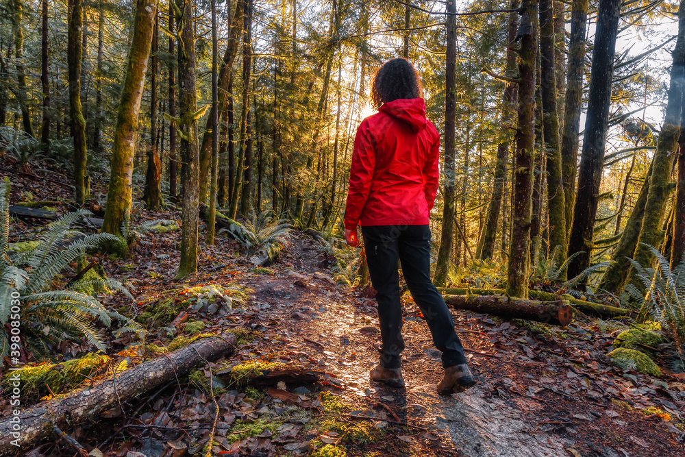 Girl Hiking on a Path in the Rain Forest during a foggy and rainy Fall Season. Squamish, North of Vancouver, British Columbia, Canada. Girl Hiking on a Path in the Rain Forest during a foggy and rainy Fall Season. Squamish, North of Vancouver, British Columbia, Canada.