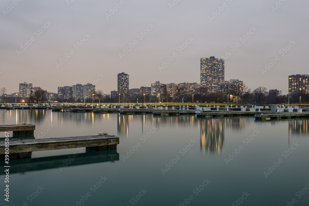 Evening lighting over calm water with empty boat docks and apartment highrises in Chicago