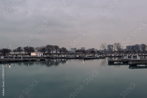 Well lit boat house behind empty docks on calm water with overcast sky in Chicago © Richard