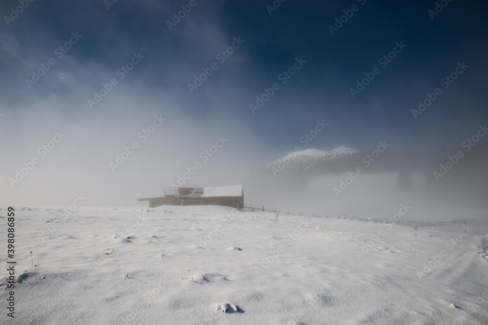 Old wooden barn high in the mountains in winter in the clouds. Thick fog. Selective focus. Blurred background.