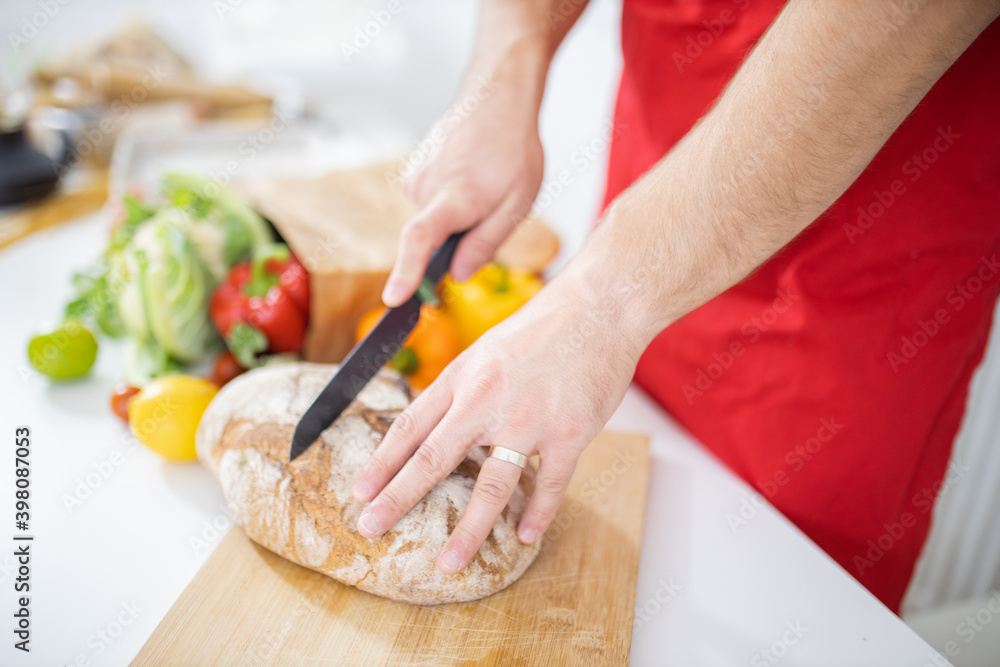 Male hands slicing bread on a cutting board