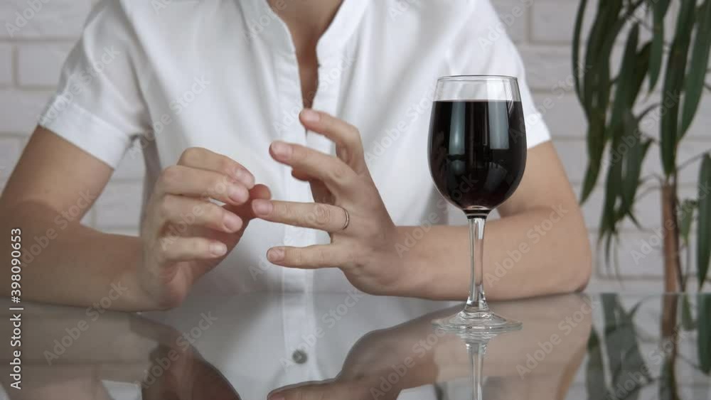 Alcohol divorce. A woman make a step to divorce and puts her ring into a glass with wine. A concept of problem with alcohol and family problems. Alcohol divorce. A woman make a step to divorce and puts her ring into a glass with wine. A concept of problem with alcohol and family problems.