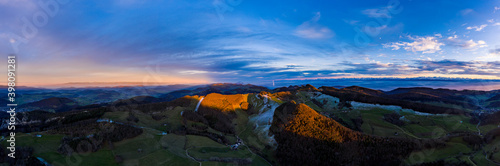 High resolution drone aerial panorama over Jura mountains and view to Swiss Central Plateau and Alps with dramatic orange sunset light and frosty shadows, Switzerland © alexander