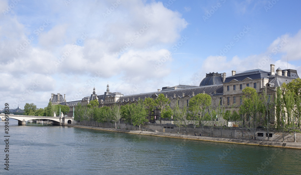 View of the Louvre from the bridge of Arts. On the promenade of Francois Mitterrand walk people