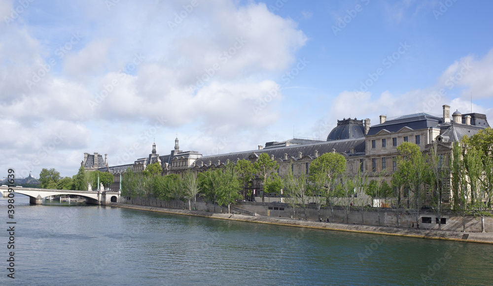 View of the Louvre from the bridge of Arts. On the promenade of Francois Mitterrand walk people View of the Louvre from the bridge of Arts. On the promenade of Francois Mitterrand walk people