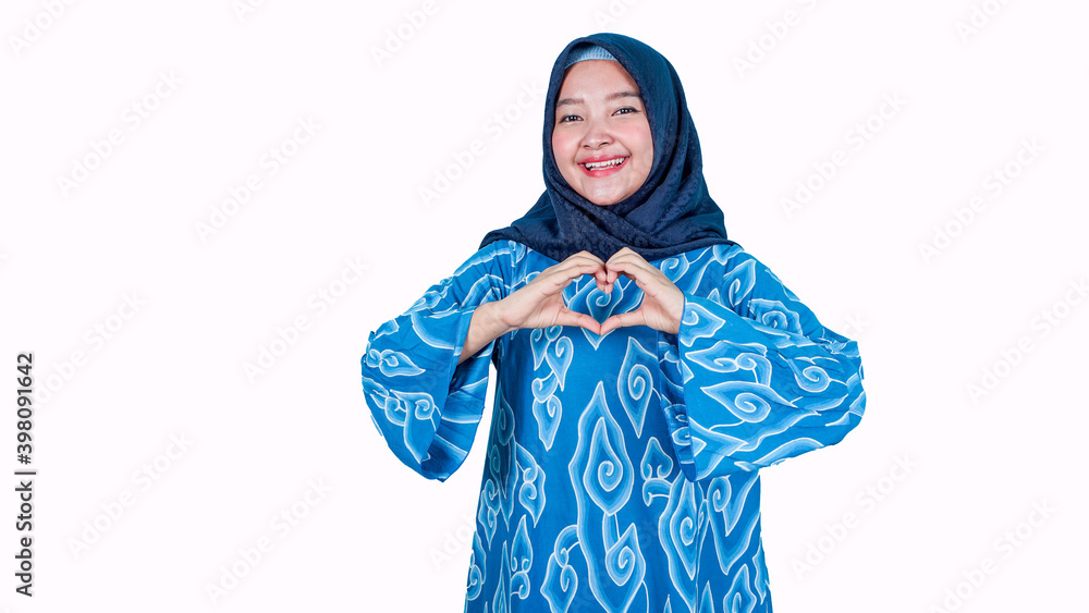 Pretty romantic asia hijab woman making a heart gesture with her fingers in front of her chest showing her love and affection - she wearing batik Indonesia traditonal clothes Pretty romantic asia hijab woman making a heart gesture with her fingers in front of her chest showing her love and affection - she wearing batik Indonesia traditonal clothes
