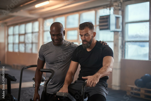 Fit man watching his workout partner on a stationary bike