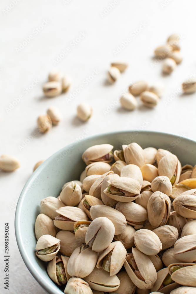 Pistachios. Pistachio nuts in a ceramic round plate, several pistachios are sprinkled on the background