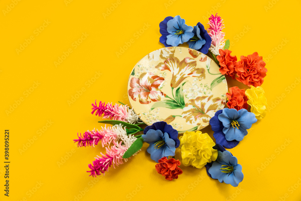 Cozy composition, design, saucer and decorative flowers on a yellow background, copy space