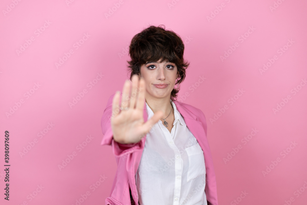 Young business woman over isolated pink background serious and doing stop sing with palm of the hand. Young business woman over isolated pink background serious and doing stop sing with palm of the hand.