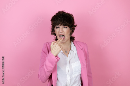 Young business woman over isolated pink background disgusted with her hand inside her mouth © Irene