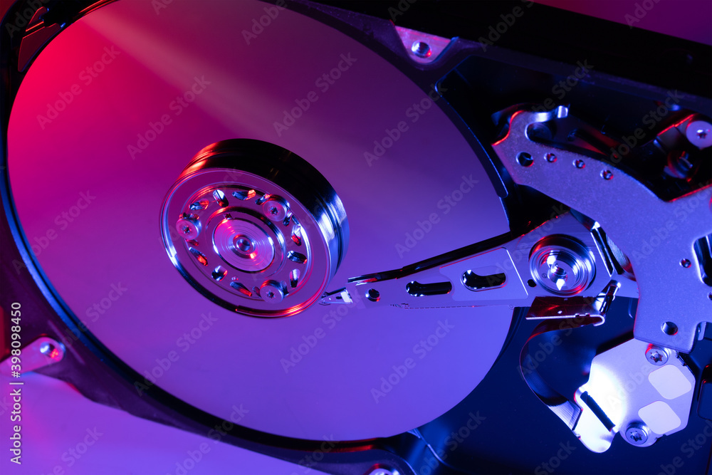 Computer hard drive HDD open with red-blue lighting close-up.