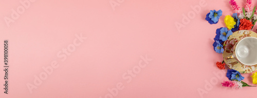 Spring composition pink background, decorative flowers and a set for a tea party, banner, copy space, top view, flat lay