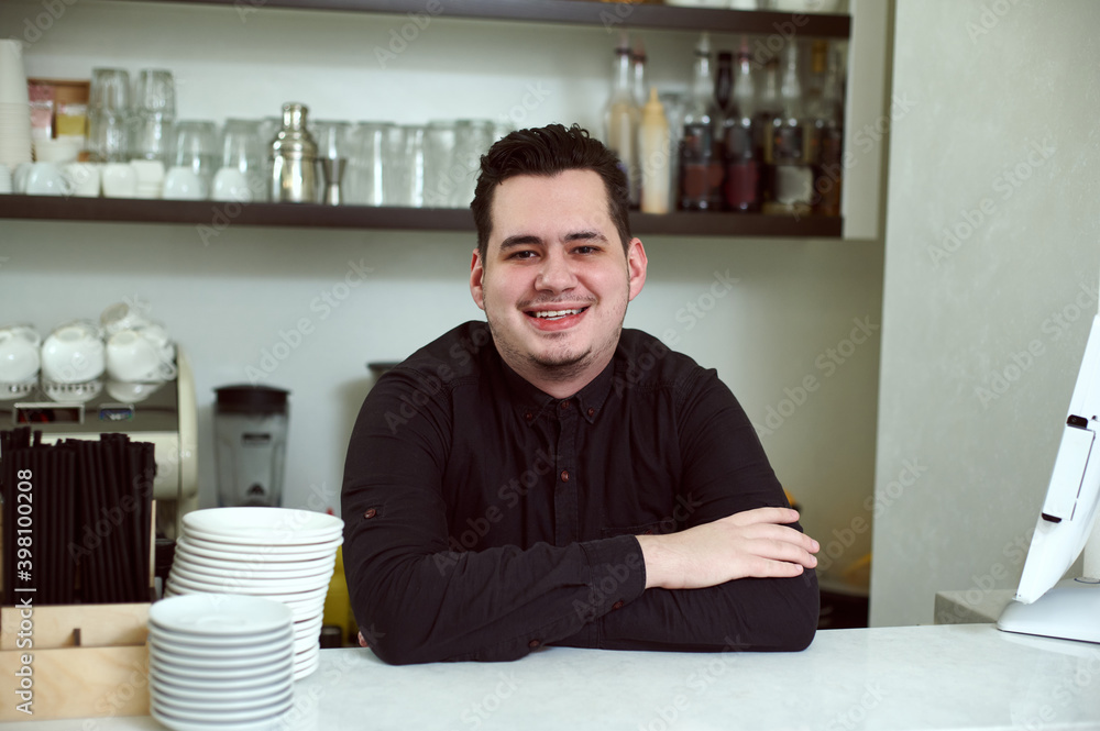 An arms crossed handsome man smiling at the camera behind the bar An arms crossed handsome man smiling at the camera behind the bar