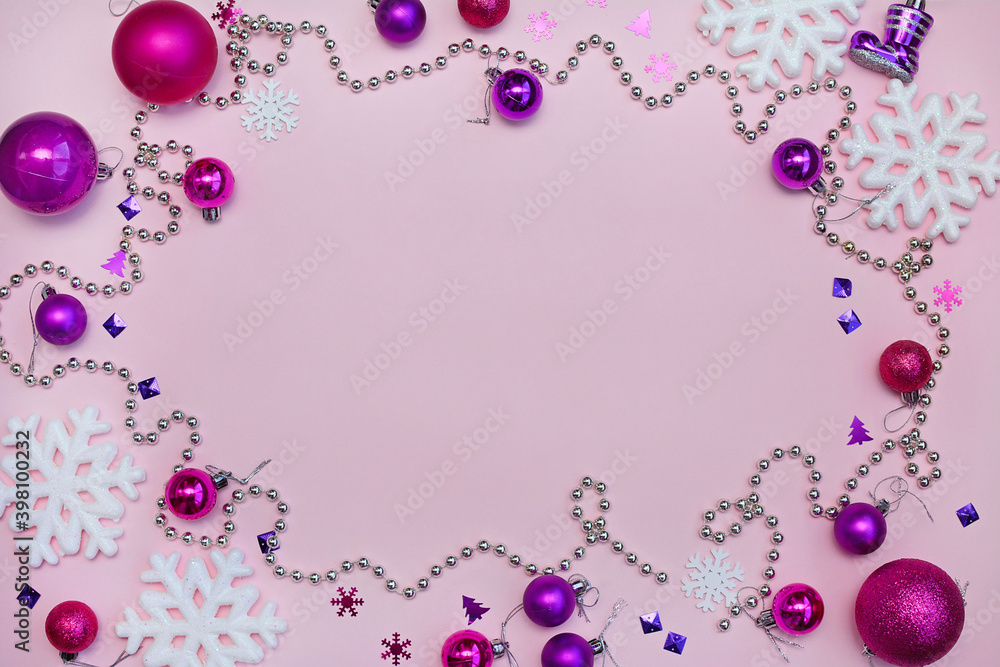 Layout of purple Christmas balls, snowflakes and beads on a pink background with copy space. View from above Layout of purple Christmas balls, snowflakes and beads on a pink background with copy space. View from above