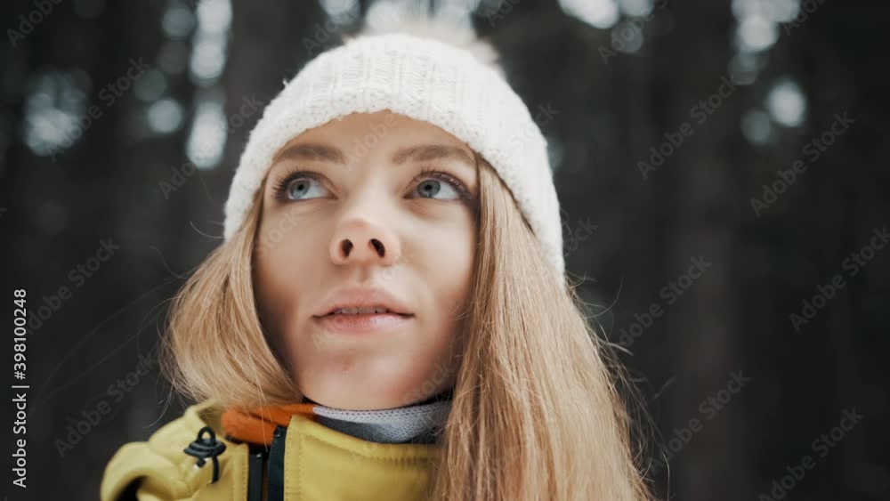 Girl with a white hat in the forest with a backpack in winter. Side view. Close up Girl with a white hat in the forest with a backpack in winter. Side view. Close up
