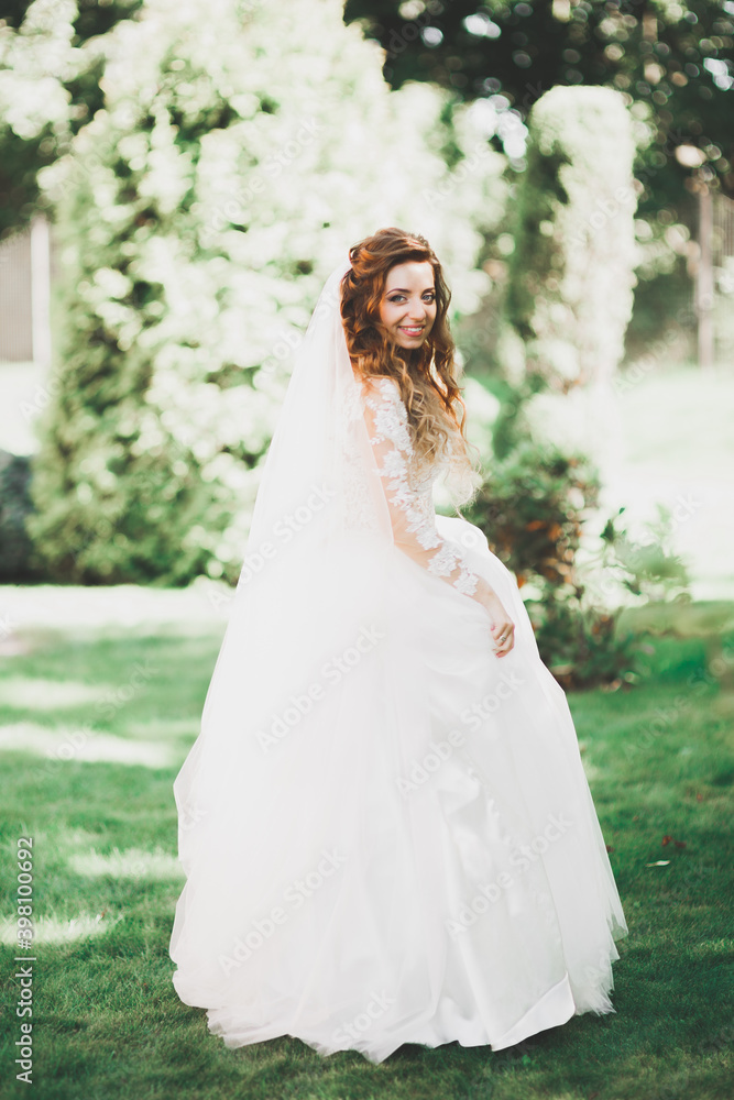 Beautiful bride in elegant white dress holding bouquet posing in park Beautiful bride in elegant white dress holding bouquet posing in park