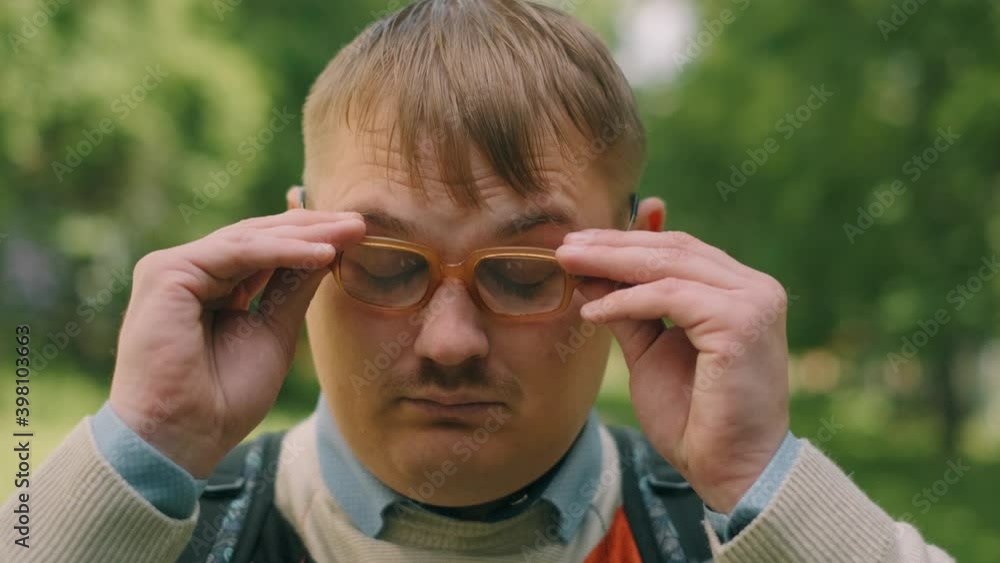 Portrait of serious nerdy man in glasses. A loser teenager is looking to the camera.
